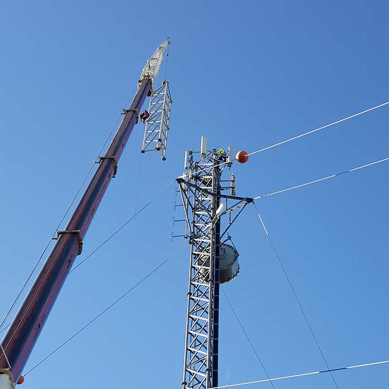 photo of crane lifting an extension for a communications tower